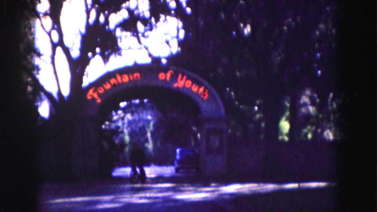 Cyclist passing near the Fountain of Youth arch in deep shade.