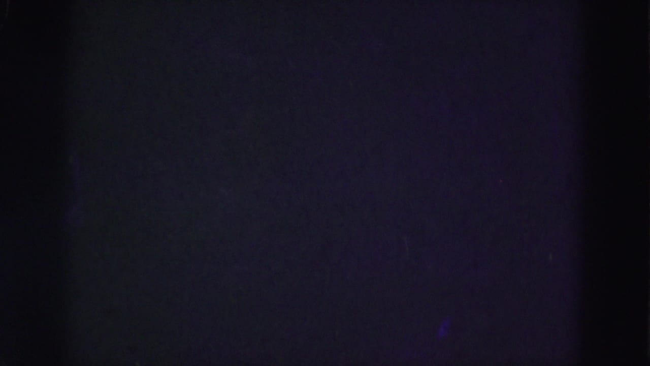 End frame from the 1975 8mm clip, mostly dark with faint purple-blue exposure and little visible scene detail.