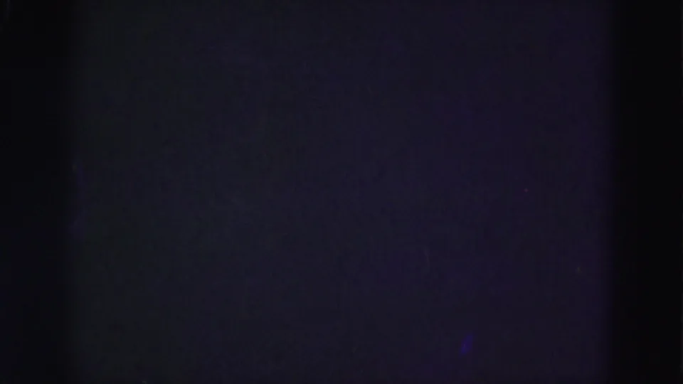 End frame from the 1975 8mm clip, mostly dark with faint purple-blue exposure and little visible scene detail.