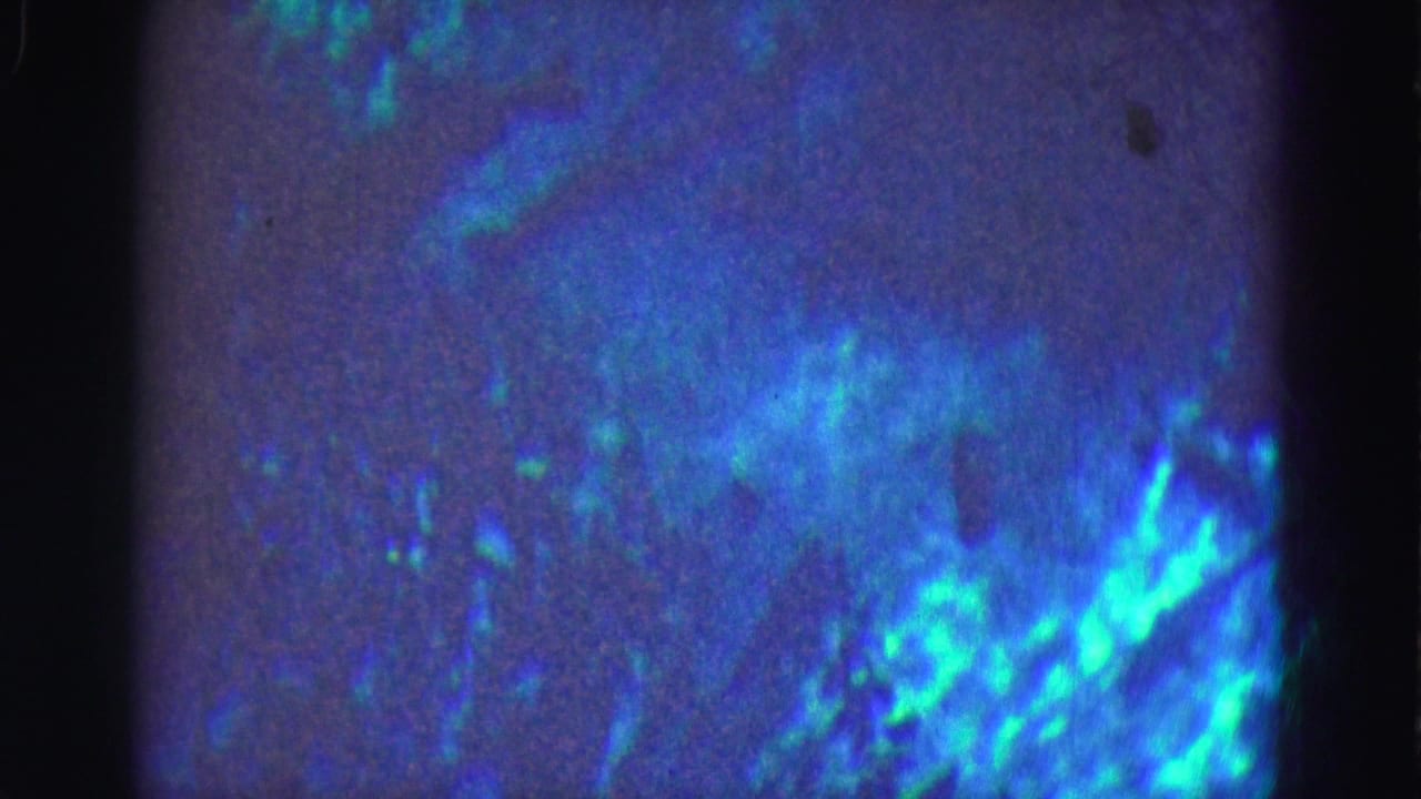 1975 8mm Florida Everglades underwater frame with turquoise mottling, soft grain, and dark vertical film borders.
