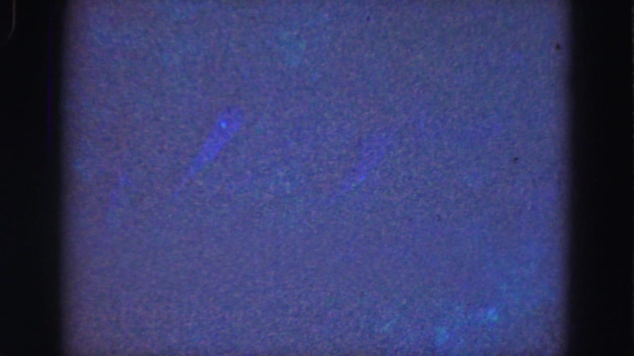 1975 Florida Everglades 8mm underwater footage showing mostly murky blue water, faint green glow, grain, and dark frame borders.