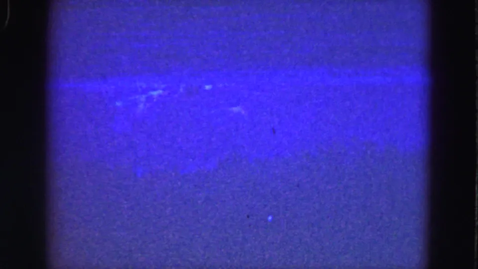 1975 8mm underwater footage showing blue water, a strong horizontal exposure band, grain, and dark rounded frame edges.