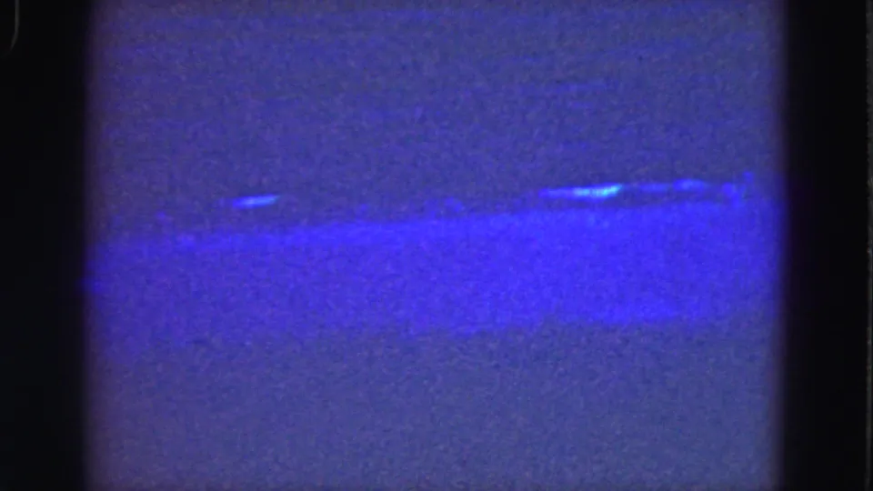 1975 Florida Everglades frame with a hazy blue water surface, faint shoreline, and visible 8mm gate edges.