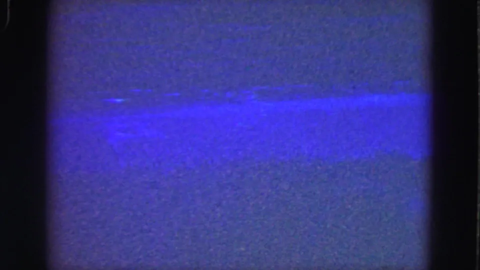 1975 Florida Everglades home-movie still showing blue water, a faint far bank, and pronounced film grain.