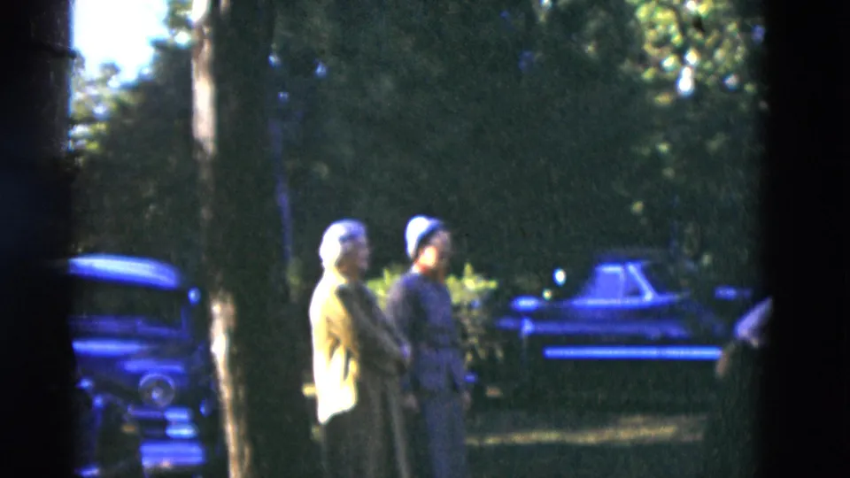 The home-movie frame shows two older women standing on a lawn in Somerset, Kentucky, with classic cars and trees in the background.