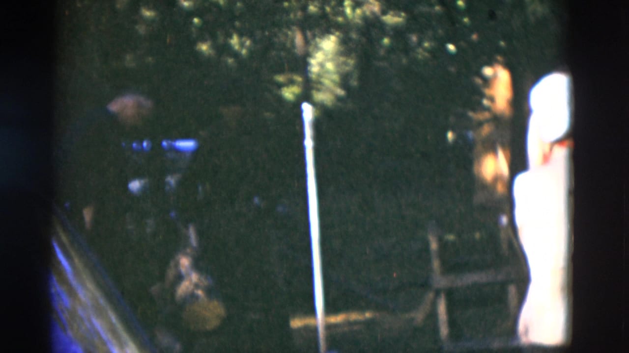 1975 Somerset, Kentucky frame with a man in a light shirt near a dark vehicle and wooded background.