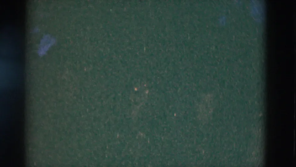 Dark 8mm home-movie frame from the Somerset, Kentucky campfire clip, with little visible detail beyond grain and edge shadows.