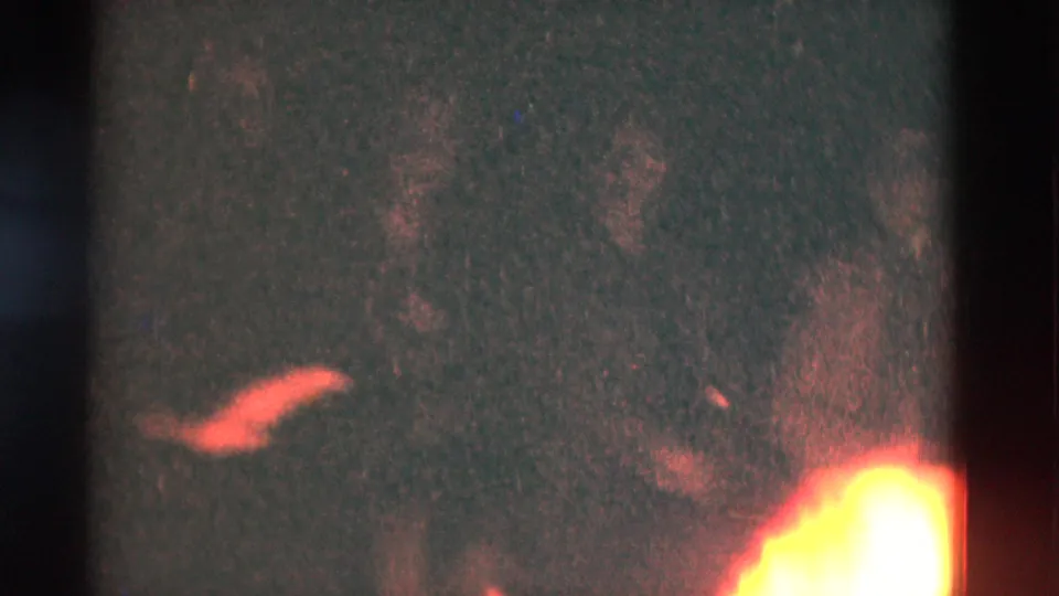 1975 Somerset, Kentucky home-movie frame with a bright campfire flare at lower right and dim red-orange detail in darkness.