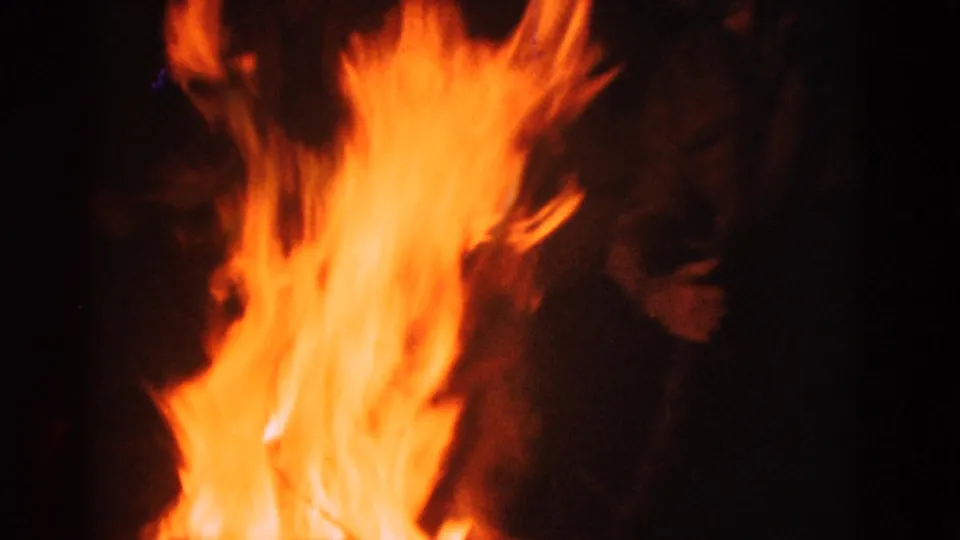 1975 8mm Somerset, Kentucky campfire scene with tall orange flames and a partially visible figure behind them in darkness.