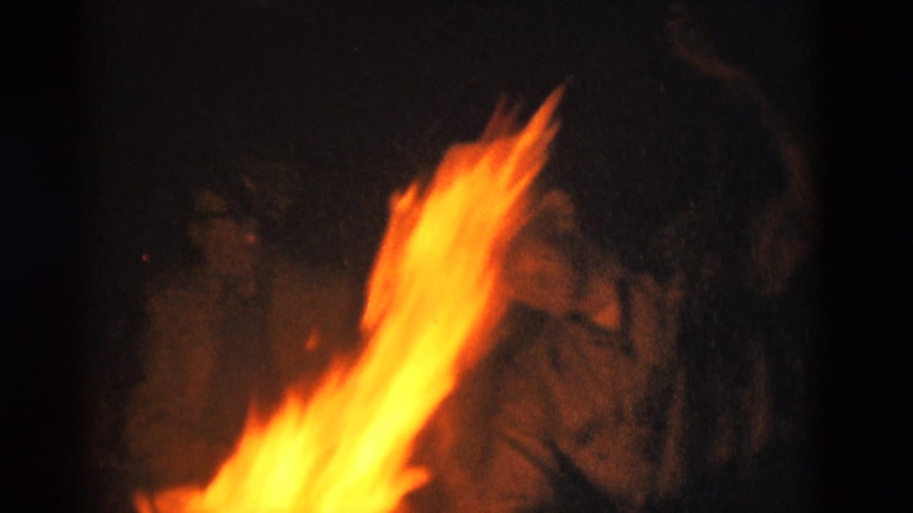 1975 Somerset, Kentucky 8mm frame with orange campfire flames dominating the foreground and campers barely visible behind them.