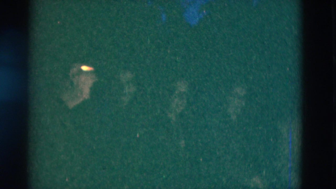 1975 8mm frame from Somerset, Kentucky with low-light green cast and faint adult faces barely visible in darkness.