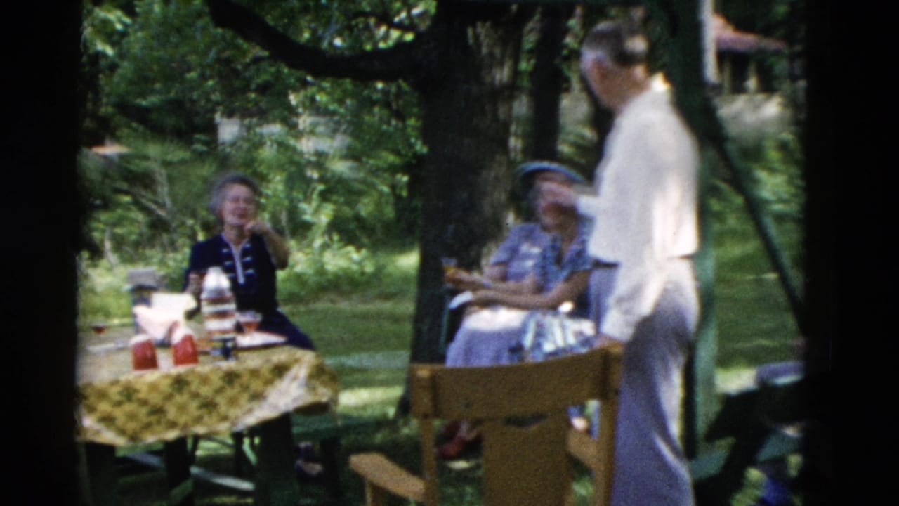 1975 Somerset, Kentucky frame with adults seated and standing around a picnic table in a leafy backyard.