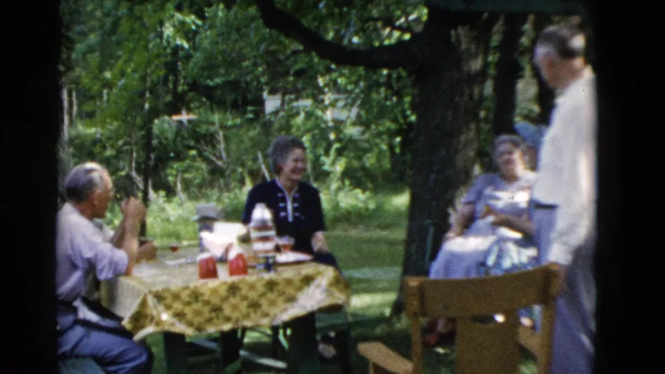 1975 Somerset, Kentucky home-movie view of adults laughing and talking around a shaded picnic table.