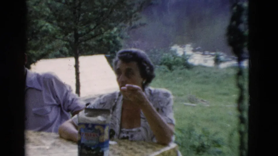 The home movie cuts to adults at an outdoor picnic table in Somerset, Kentucky, with cups and a food container in the foreground.
