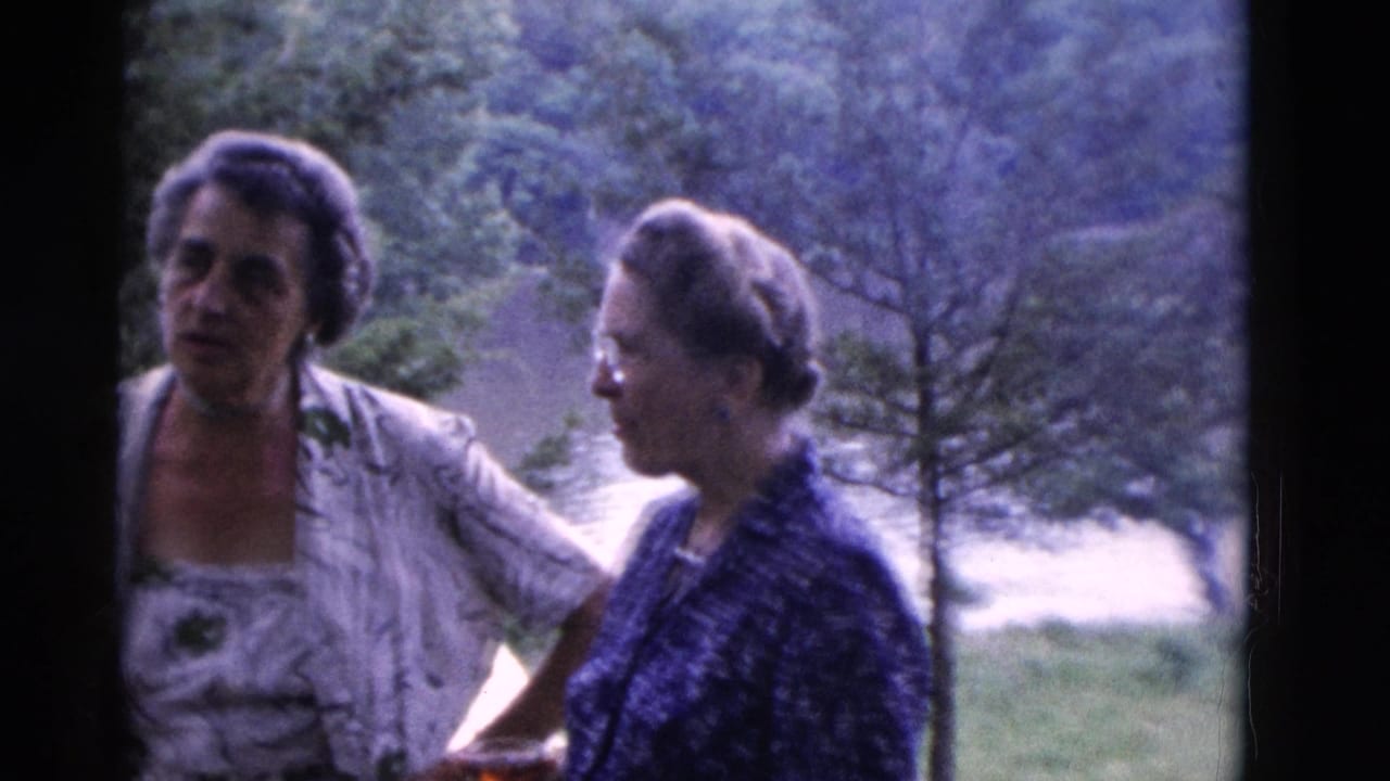 Two women in patterned 1970s clothing converse outdoors in Somerset, Kentucky, with wooded scenery behind them.