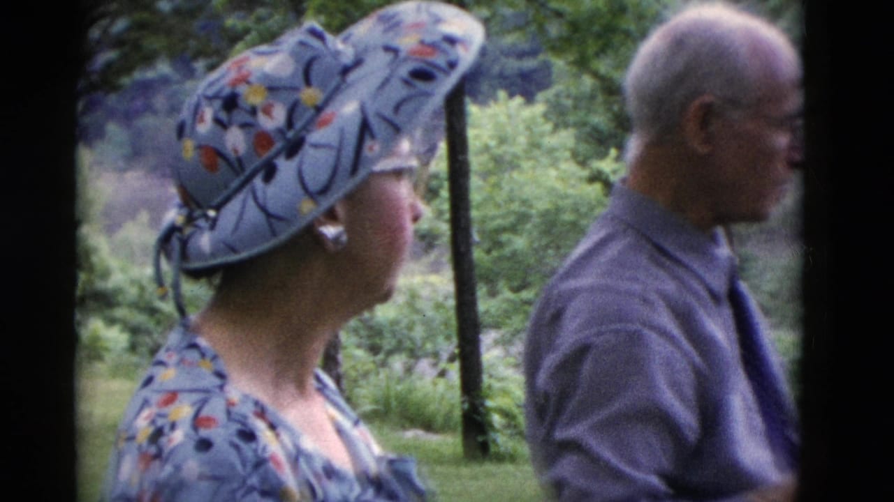 Somerset, Kentucky 1975 home-movie frame showing adults gathered outside, with a floral sunhat, patterned clothing, and wooded greenery behind them.