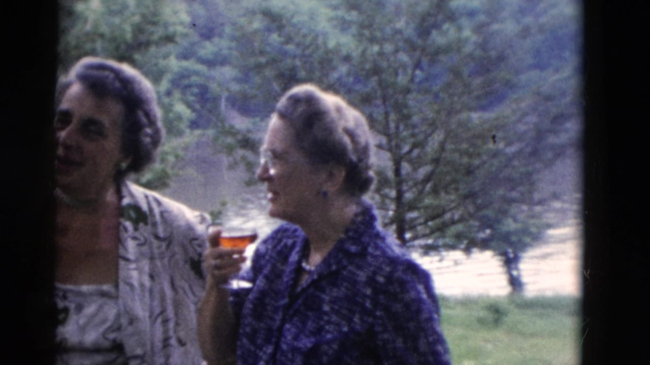 Somerset, Kentucky 1975 frame of two adult women conversing outside near trees and water, one holding a reddish drink in a glass.