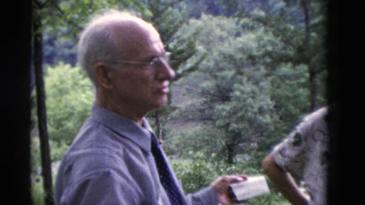 An older man in glasses and a tie stands in profile in wooded Somerset, Kentucky home-movie footage from 1975.