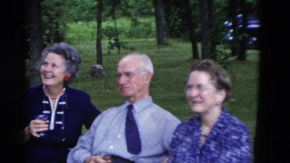 A 1975 Somerset, Kentucky backyard scene shows two women and an older man seated among trees, with drinks visible.