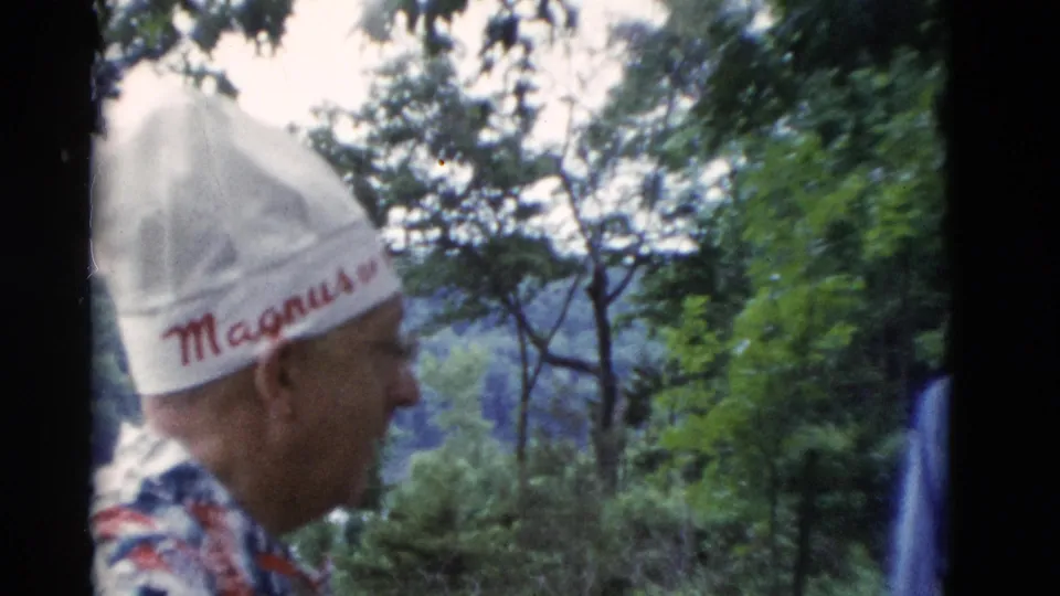 1975 Somerset, Kentucky 8mm frame showing a man in a white Magnus hat standing in profile in a wooded backyard.