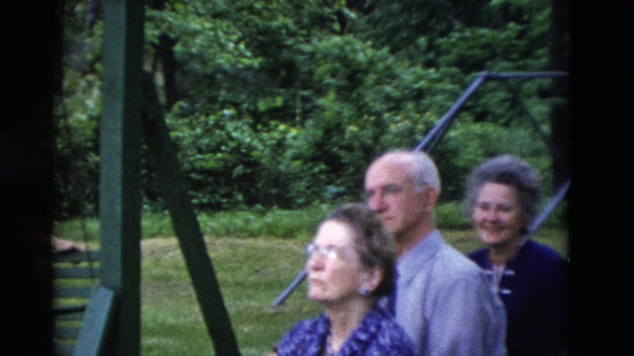 1975 Somerset, Kentucky frame with older adults gathered near green swing-set supports in a leafy backyard.