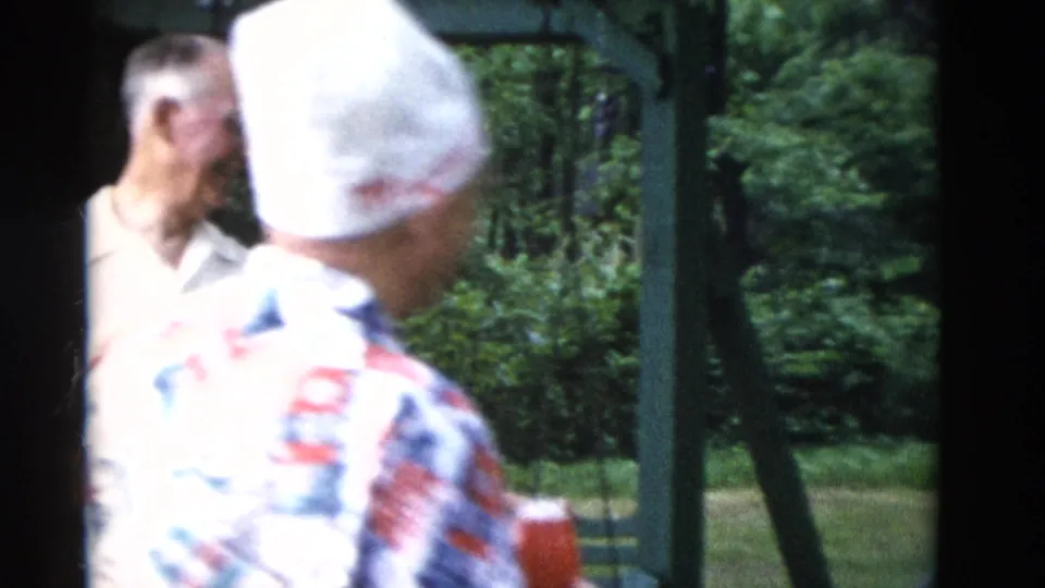 1975 Somerset, Kentucky home-movie frame showing a man in a white cap and patterned shirt near older adults outdoors.