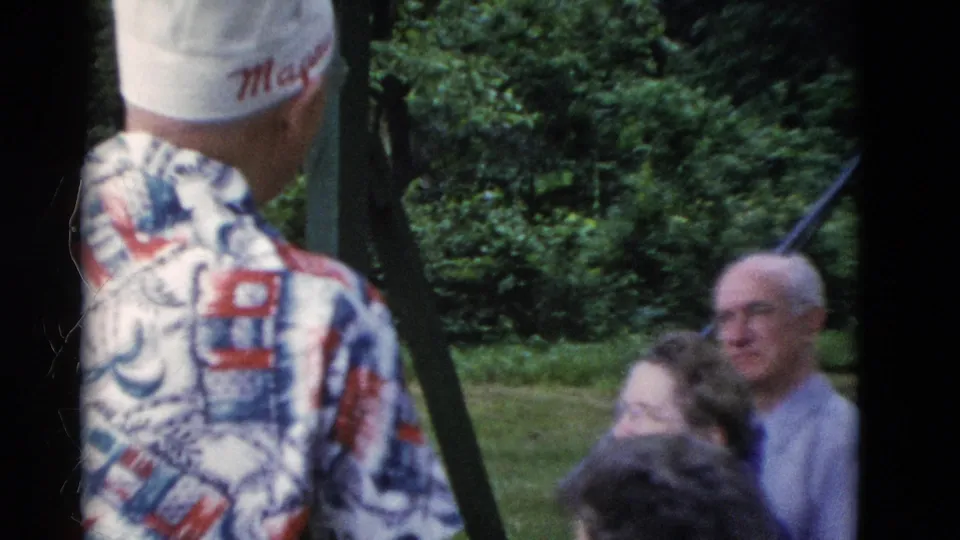 Older adults, including a smiling bald man and a woman with glasses, appear near a man in a white cap outdoors.