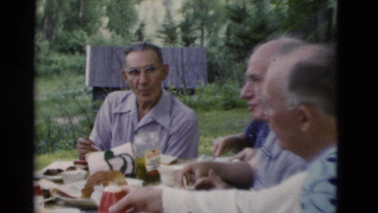 Older adults at an outdoor picnic table in Somerset, Kentucky, in 1975, with food, cups and trees behind them.