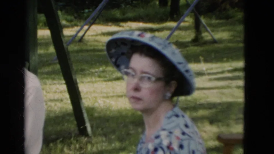 The woman in a patterned sunhat and glasses faces the camera in a grassy Somerset, Kentucky outdoor gathering from the supplied 1975 metadata.