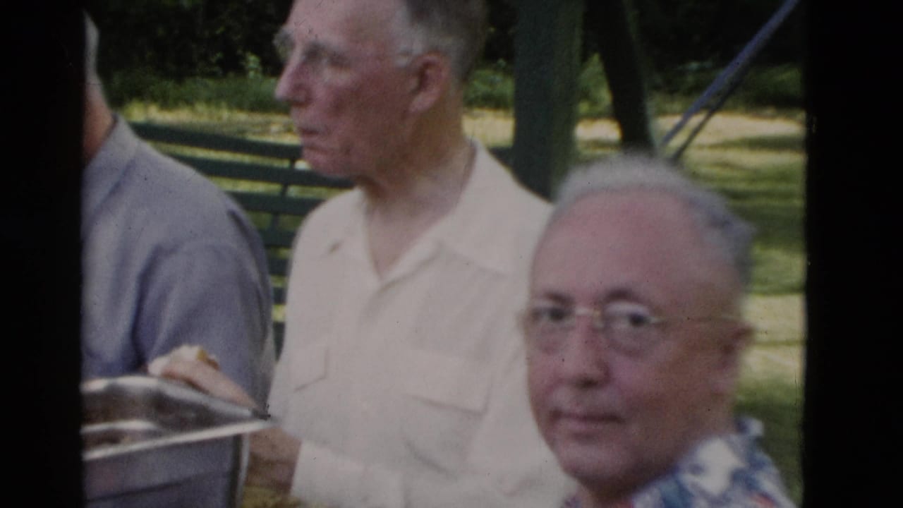 1975 Somerset, Kentucky home-movie frame showing older men at an outdoor meal table in a park setting.