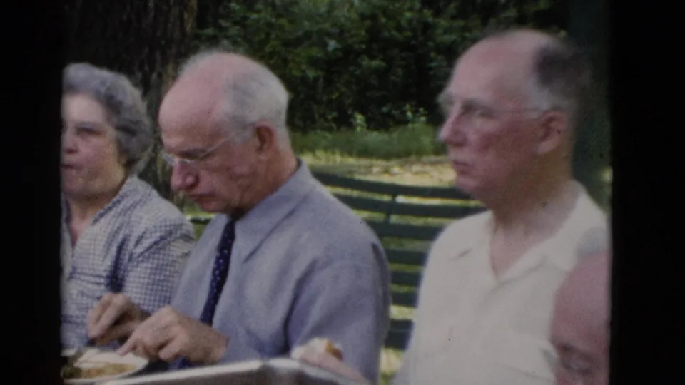 1975 Somerset, Kentucky frame of older adults eating together outdoors at a shaded park table.