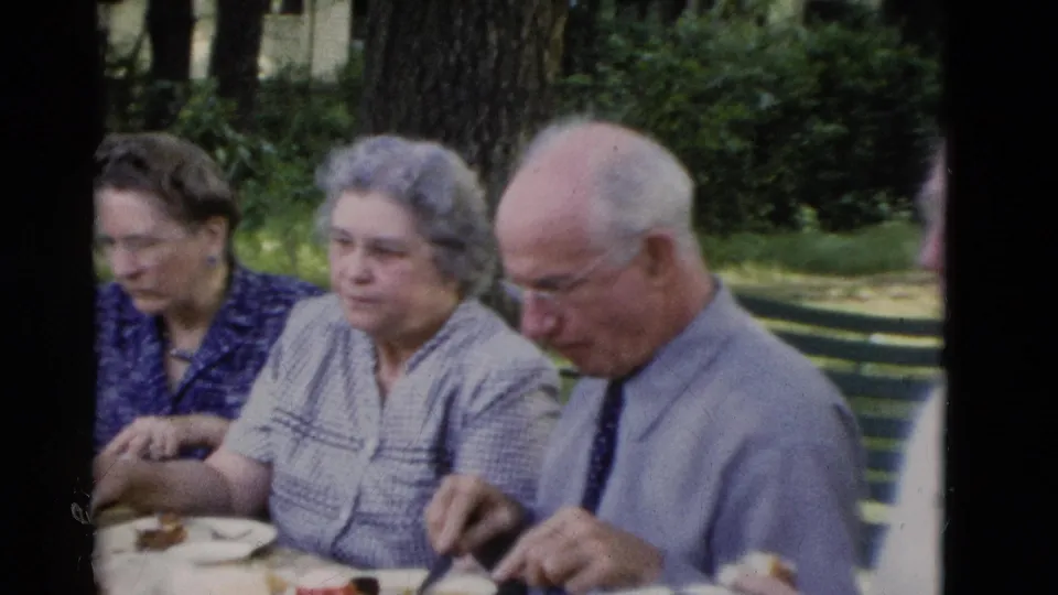 Older adults in a 1975 Somerset, Kentucky park scene sit together at an outdoor meal table.