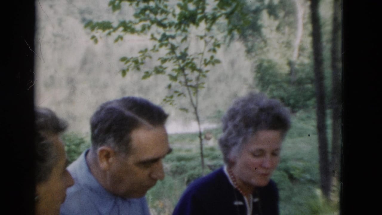 Somerset, Kentucky 1975 home-movie frame of an older man in a light blue shirt beside older women in a wooded outdoor setting.