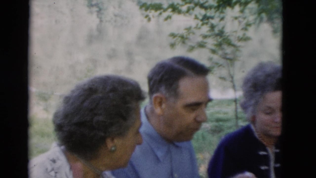 Older women and an older man appear in close handheld 8mm footage outdoors in Somerset, Kentucky, with trees and greenery behind them.