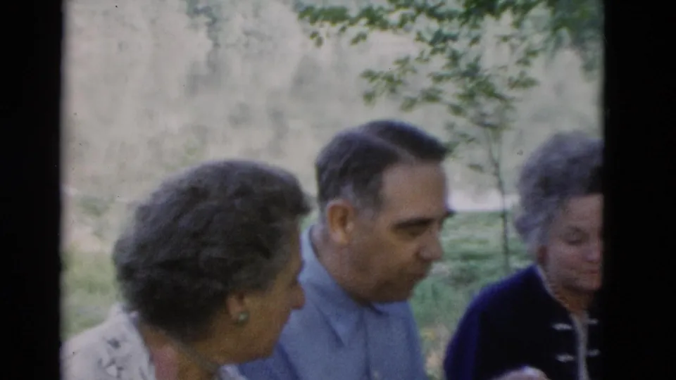 Older women and an older man appear in close handheld 8mm footage outdoors in Somerset, Kentucky, with trees and greenery behind them.