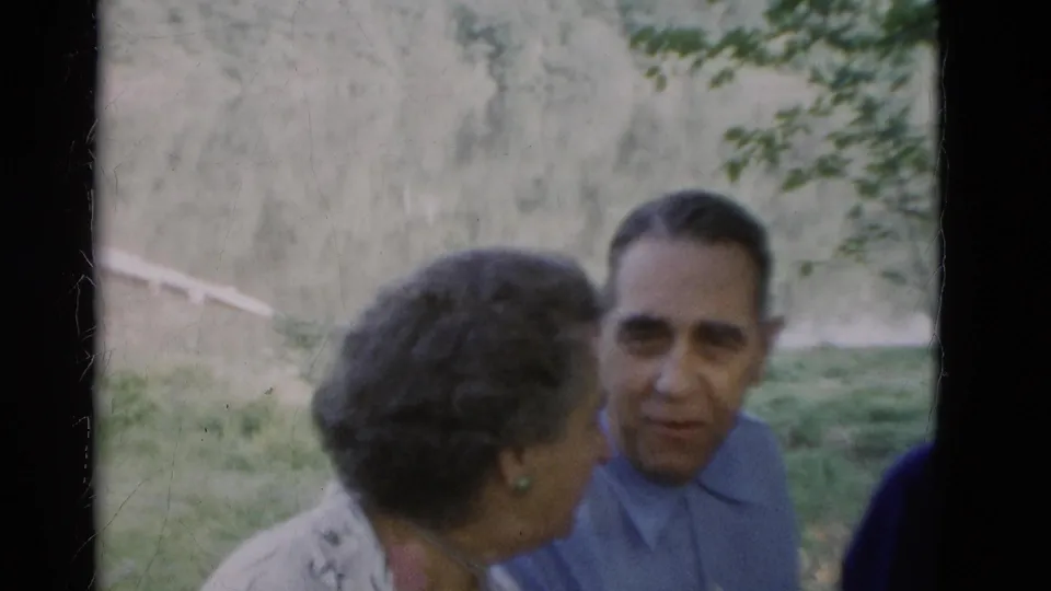 Close 1975 home-movie view of an older woman turned toward an older man outdoors in wooded Somerset, Kentucky surroundings.