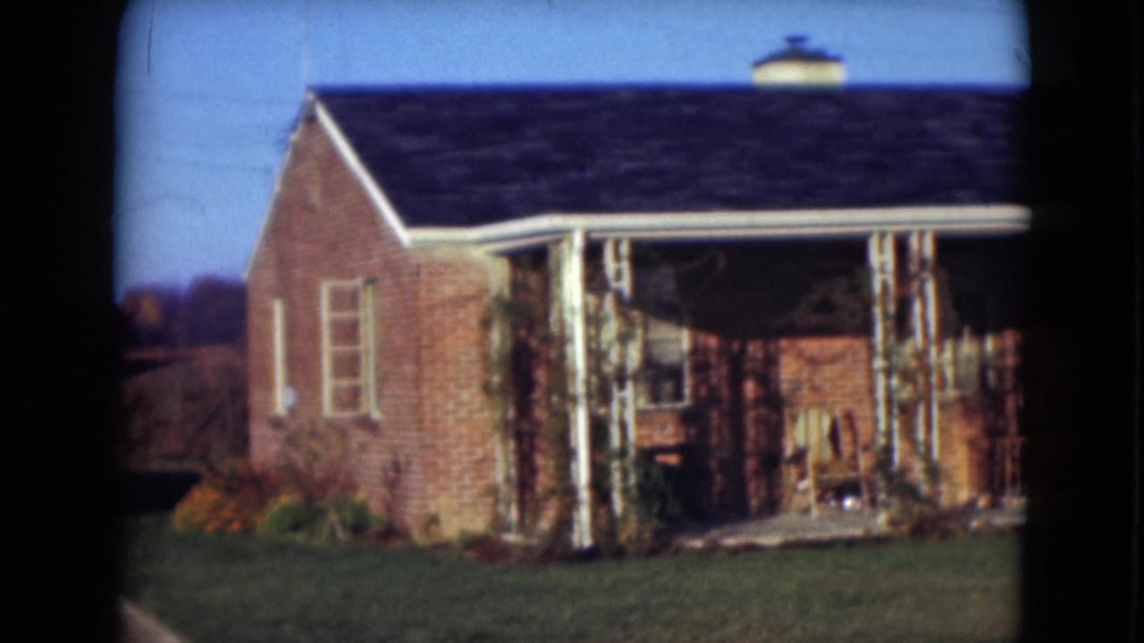1975 Middletown, Pennsylvania home-movie view of a brick house from the side, with porch columns and lawn visible.