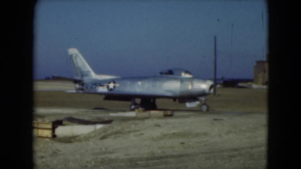 1975 Middletown, Pennsylvania 8mm frame showing a parked jet marked 250 beside runway equipment and a low airfield building.