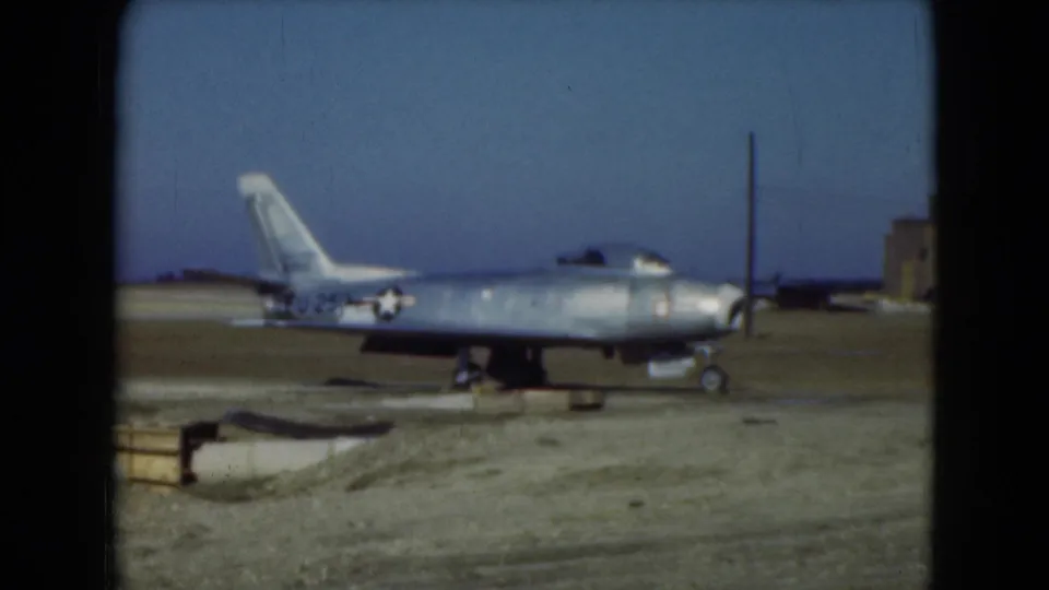1975 Middletown, Pennsylvania 8mm frame showing a silver military jet with U.S. star marking on a dusty airfield.