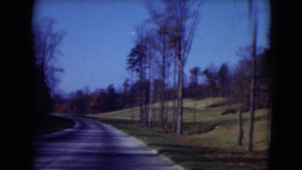 1975 Middletown, Pennsylvania driving view with a curving road, bare trees and rolling green roadside land.