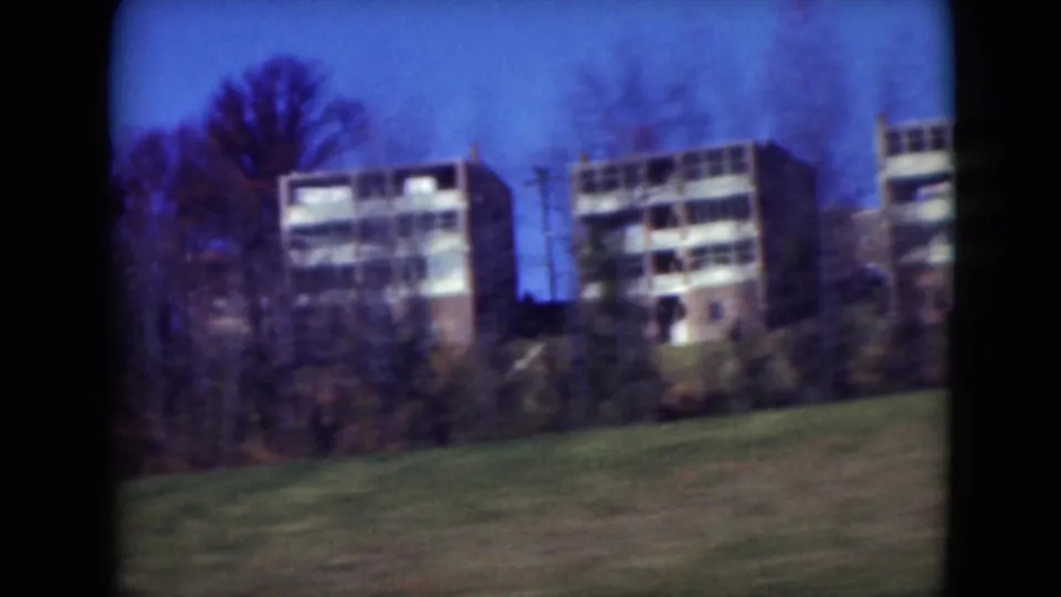 1975 Middletown, Pennsylvania frame showing apartment buildings behind trees and a grassy slope from a moving roadside viewpoint.