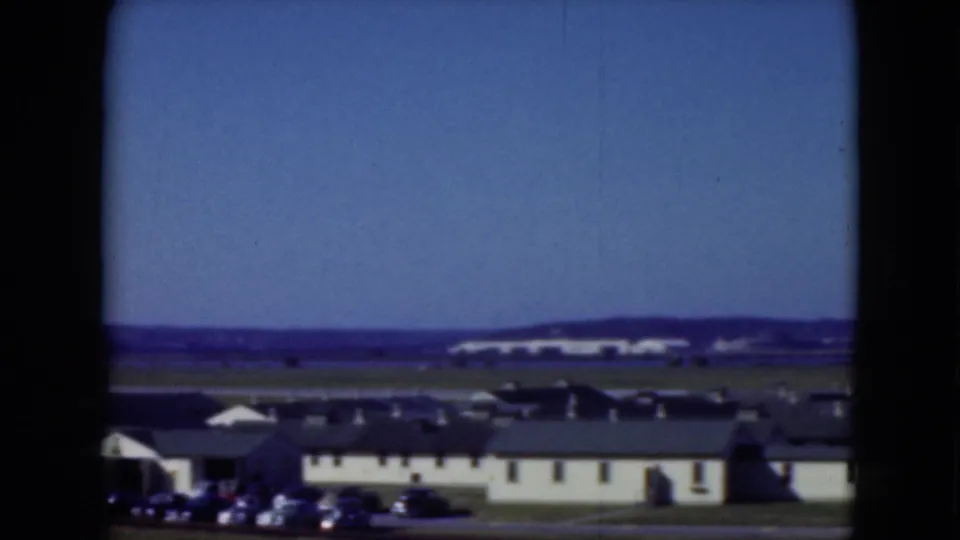 Middletown waterfront scene in 1975, with a long low building, parked cars, water, and distant land visible.