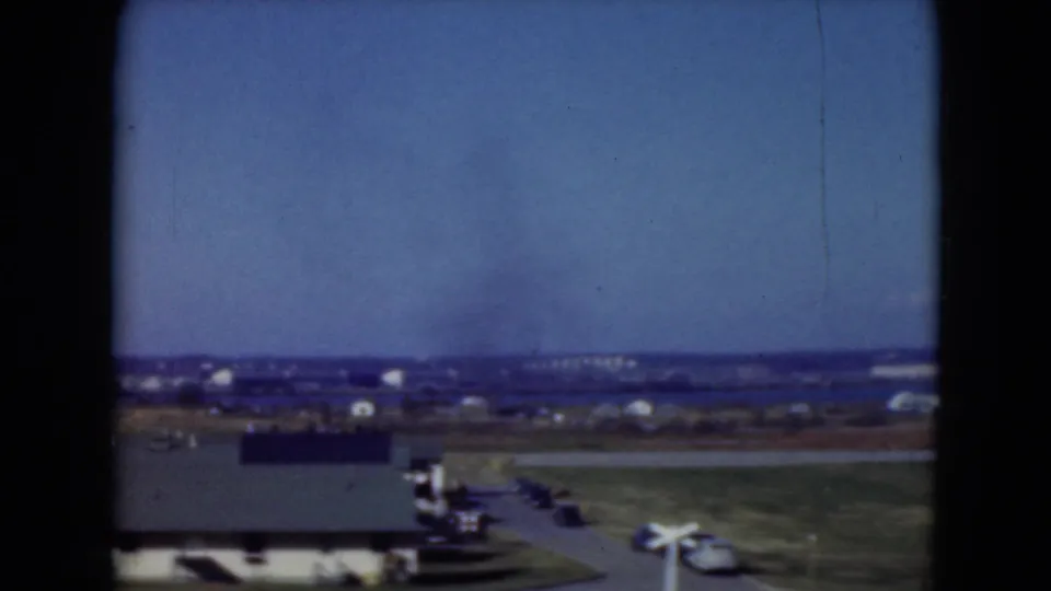Middletown, Pennsylvania 1975 frame with a crossing signal, small aircraft, road, low buildings, and open airfield-like land.