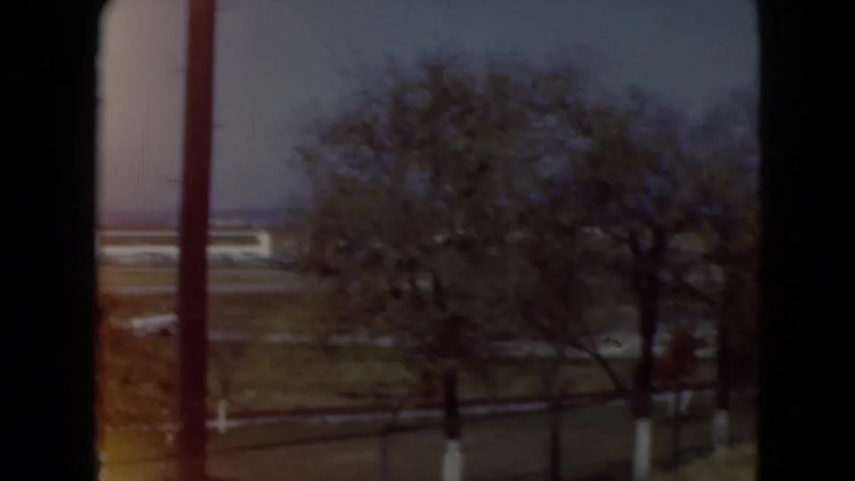 Open field, bare tree, fencing, and distant structures appear in Middletown, Pennsylvania 1975 home-movie footage.