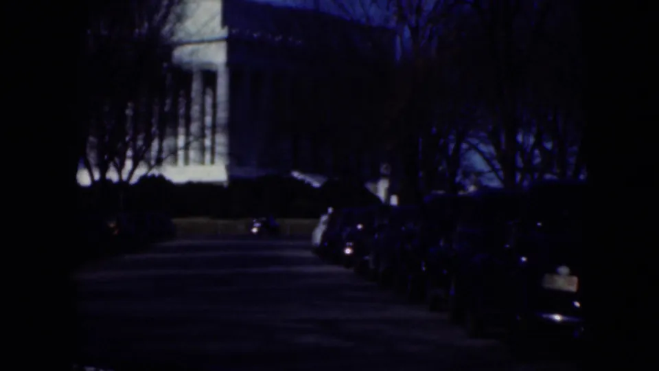 1975 Middletown street view showing parked cars, a classical-looking columned building, shrubs, bare trees, and deep blue shadow.