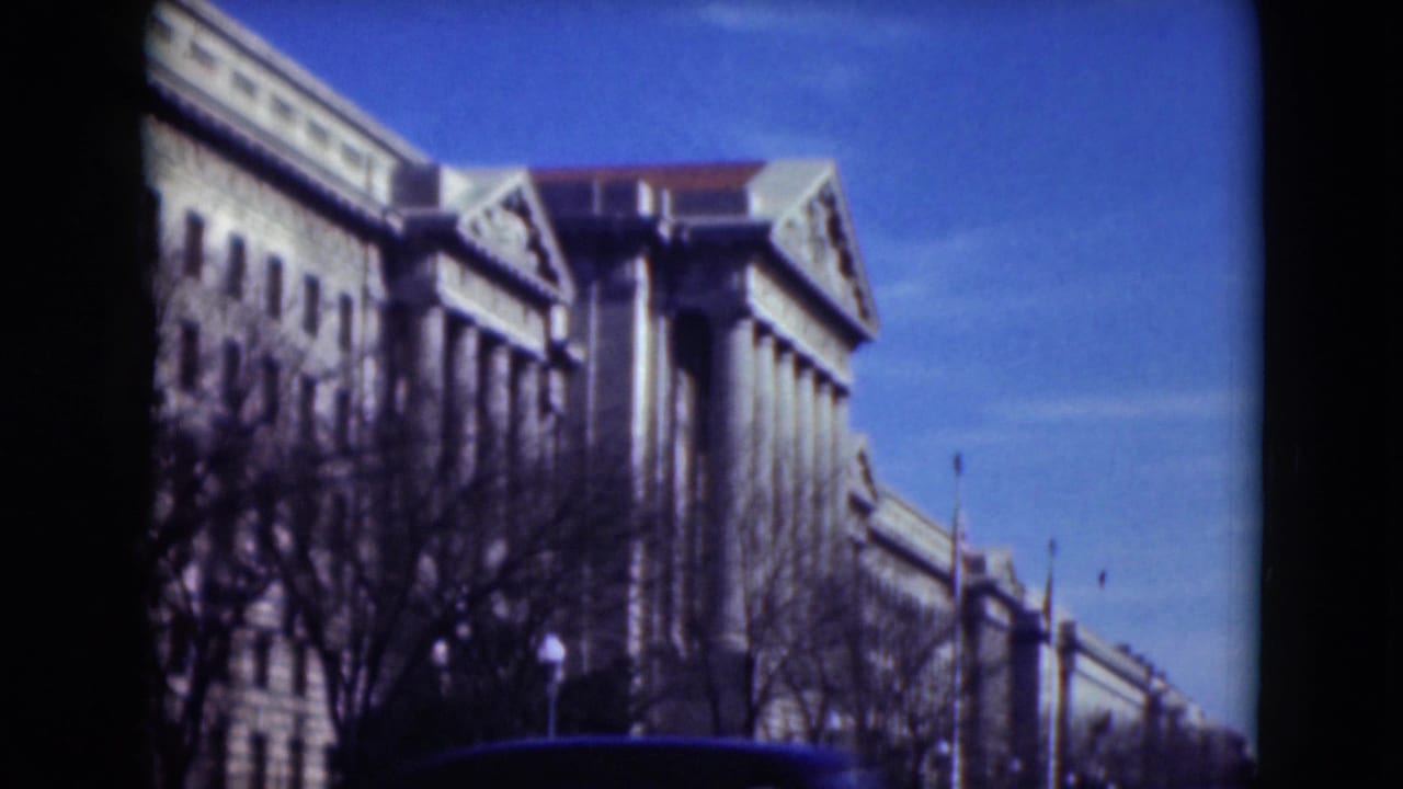 Large columned building in Middletown, Pennsylvania, filmed on 8mm in 1975 with bare trees, a street flag, and blue sky visible.