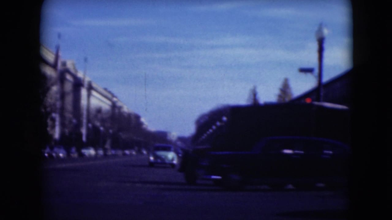 Broad Middletown street scene with 1970s automobiles, distant pedestrians, parked cars, and large buildings along the left side.