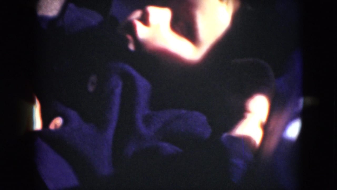 1975 8mm home-movie frame from Middletown metadata showing a reclining person in a dark interior with warm highlights and blue-purple shadows.