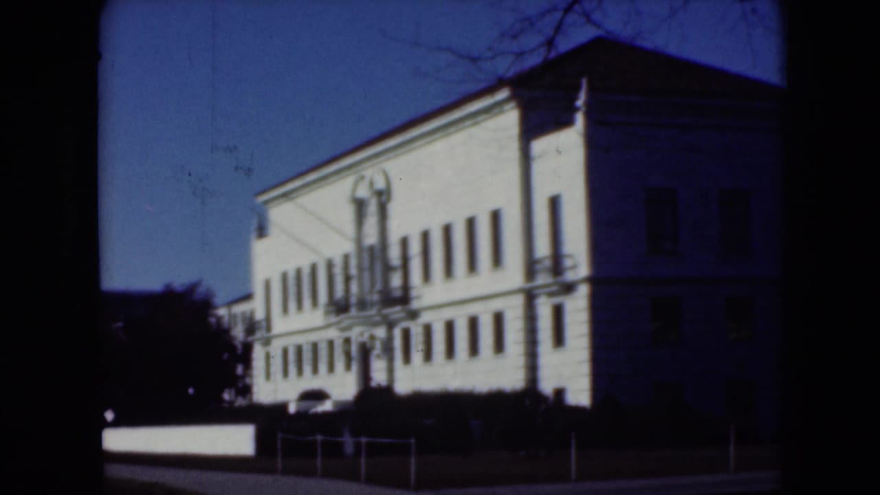 1975 8mm frame from Middletown, Pennsylvania showing a large white institutional building with a central entrance and rows of windows.