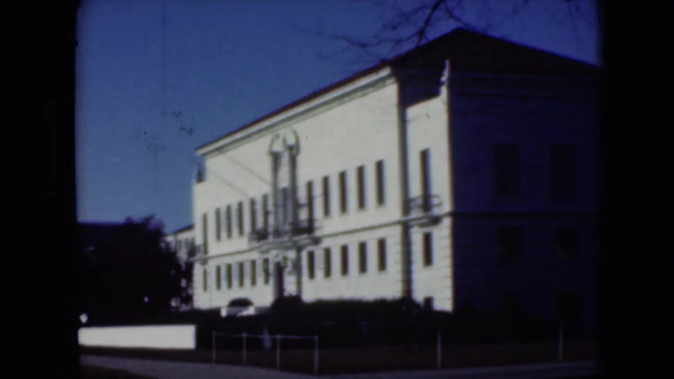1975 8mm frame from Middletown, Pennsylvania showing a large white institutional building with a central entrance and rows of windows.